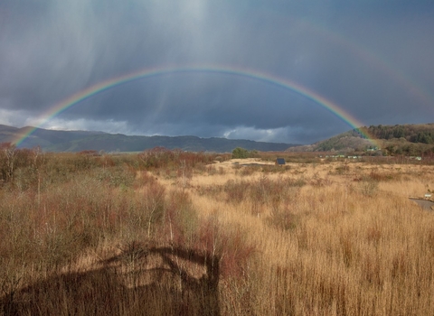 Looking over the Cors Dyfi Nature Reserve, with a rainbow arcing across the sky