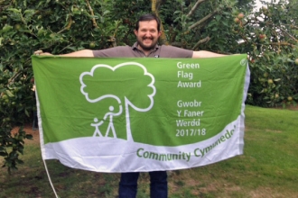 Warden of Severn Farm Pond holding the Green Flag Award flag