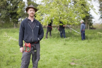 Laurence standing in an orchard