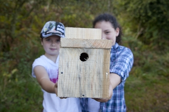 Two young children holding up a handmade bird box
