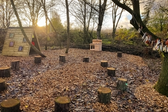A nature play area with log stools and rainbow room