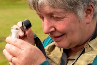 A lady examining a moth in a pot