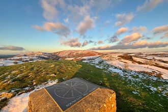 A view from the top of Roundton Hill, looking over the hills with light snow on them