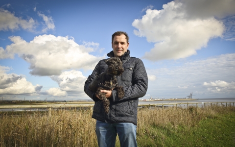 David holding his dog at a wetland