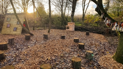 A nature play area with log stools and rainbow room