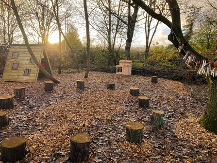 A nature play area with log stools and rainbow room