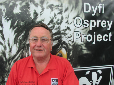 Longstanding MWT volunteer, Peter Murdoch, standing in front of a Dyfi Osprey Project poster