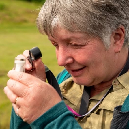 A lady examining a moth in a pot