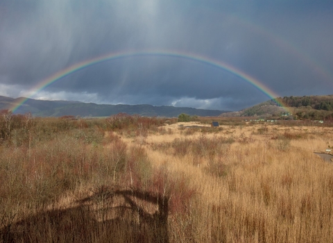 Looking over the Cors Dyfi Nature Reserve, with a rainbow arcing across the sky