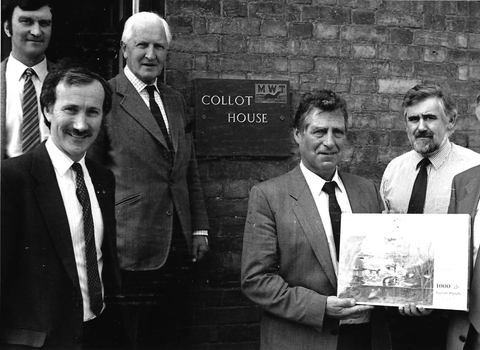 A group of gentlemen standing around a sign that reads Collot House