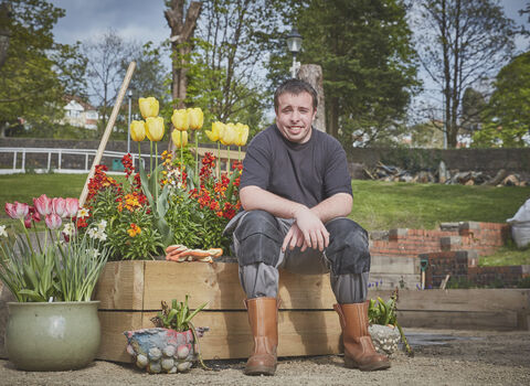 Man sitting by colourful plants