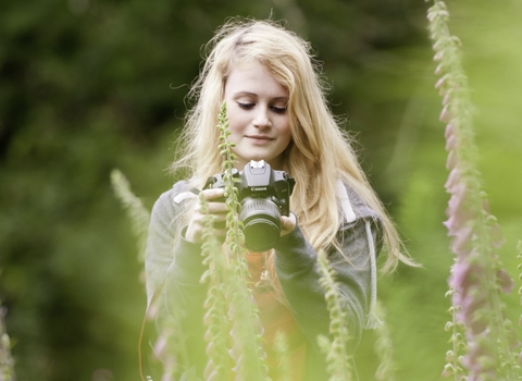 Visitor, Jazz Dyson, enjoys and photographs foxgloves {Digitalis purpurea} growing at Denmark Farm Conservation Centre, Lampeter, Wales, UK. June 2011. (Model released) - Ross Hoddinott/2020VISION